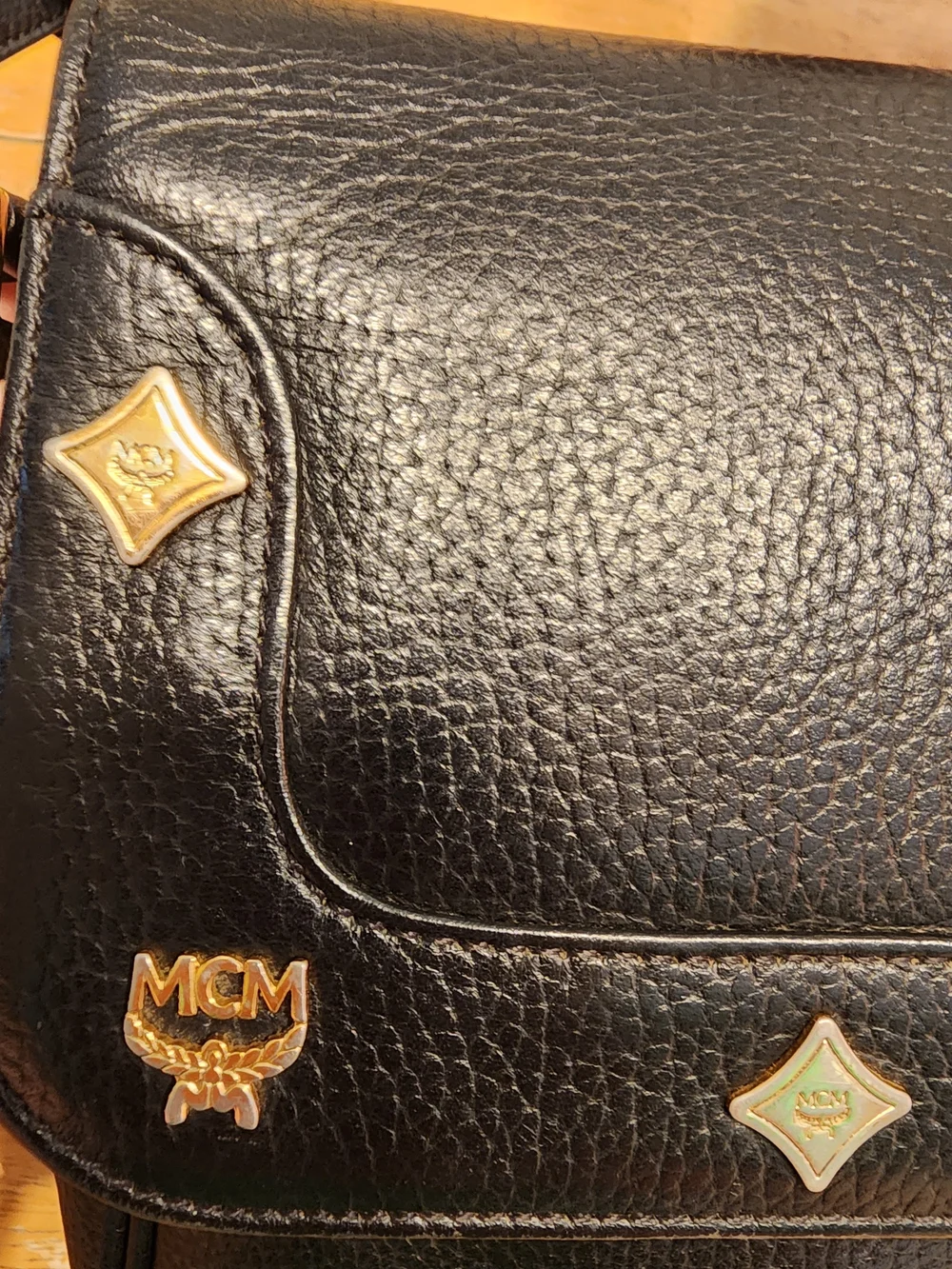 vintage MCM black pebbled leather studded crossbody bag featuring a front plaque